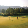 A sunny view of a hole with a cart path in background at The Omni Grove Park Inn